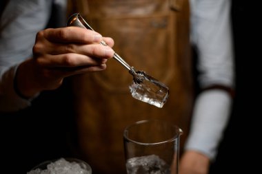 Profesyonel barmen ölçüm cam fincan için büyük bir buz küpü koyarak