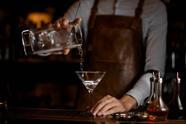 Barman professionnel versant une boisson alcoolisée de la tasse à mesurer au verre de martini — Photo