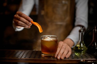 Profesyonel erkek barmen cam altın bir kokteyl için bir portakal lezzet suyu ekleyerek