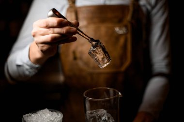 Profesyonel erkek barmen ölçüm cam fincan için büyük bir buz küpü koyarak