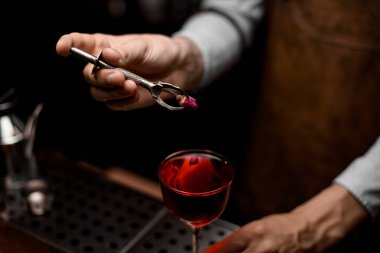 Barmen cam kırmızı kokteyl için küçük bir gül tomurcuk koyarak