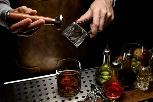 Male bartender making a stamp imprint on the big ice cube