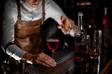 Profesyonel barmen karanlıkta kırmızı alkollü kokteyl püskürtme