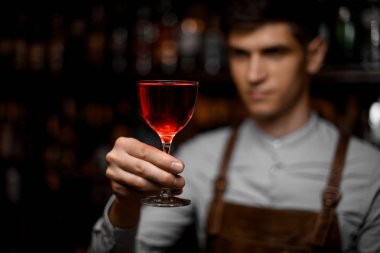 Bardakta kırmızı alkollü kokteyl servis eden erkek barmen