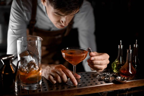 Привлекательный бармен кладет ягоды на шампур на коктейльный бокал — стоковое фото