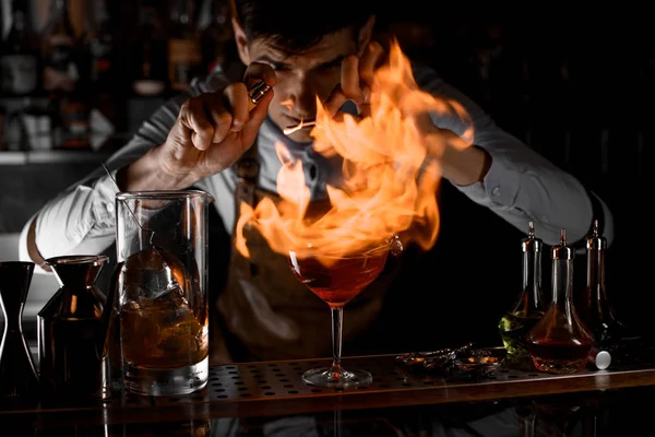 Cantinero rociando en el fuego alrededor de la copa de cóctel — Foto de Stock