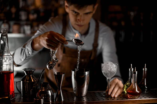 Barman atraente derramando uma essência da colher na chama para a coqueteleira de aço — Fotografia de Stock