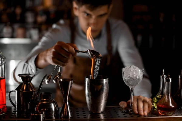 Профессиональный бармен наливает эссенцию из ложки в пламя в стальной шейкер — стоковое фото