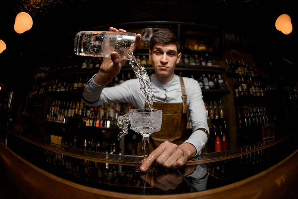 Fischaugenschuss professioneller Barkeeper, der einen Cocktail aus dem Messbecher ins Glas gießt — Stockfoto