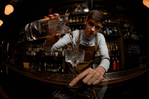 Профессиональный бармен с рыбьим глазом наливает коктейль из мерной чашки в стекло — стоковое фото