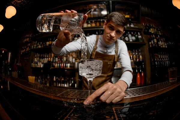 Fisheye shot attraktiver Barkeeper, der einen Cocktail aus dem Messbecher ins Glas gießt — Stockfoto