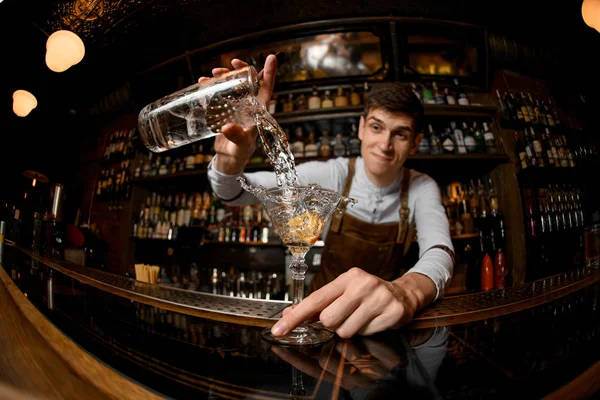 Fisheye shot leende bartender hälla en cocktail från mätkoppen till glaset — Stockfoto