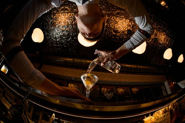 Unten Fischaugenschuss Barkeeper, der einen Cocktail aus dem Messbecher in das Glas gießt — Stockfoto