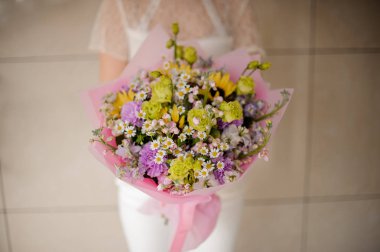 İhale yeşil ve menekşe çiçekler ve küçük papatya bir bahar buket tutan kız