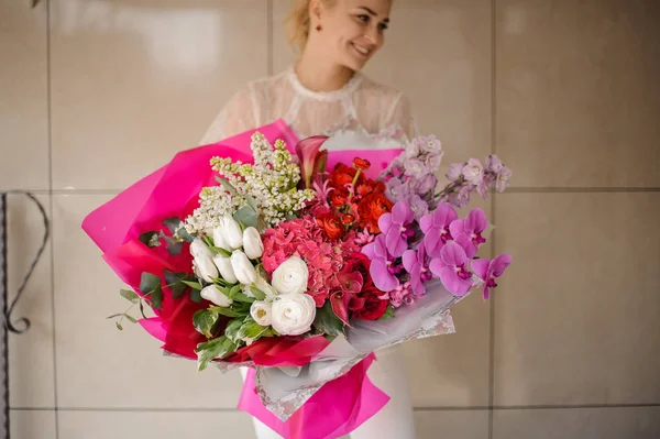 흰색 튤립과 라일락, 핑크 난초와 수국과 빨간 장미의 꽃다발을 들고 미소 소녀 — 스톡 사진