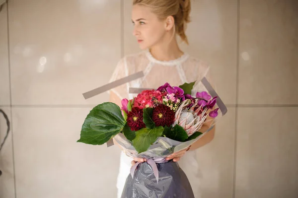 Chica sosteniendo un ramo de primavera de flores rojas, rosas, violetas y carmesí — Foto de Stock