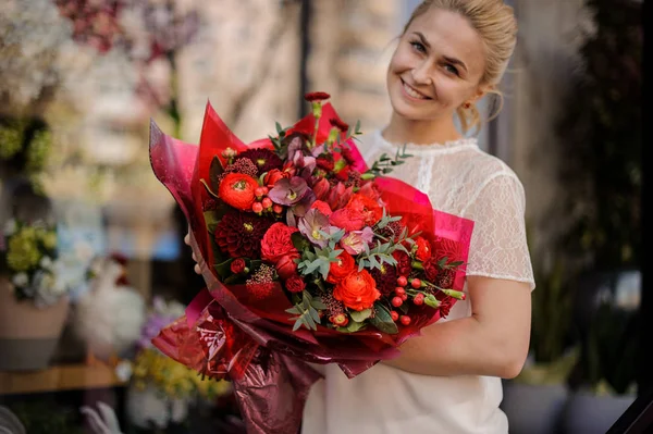 Menina sorridente segurando um buquê de flores vermelhas carmesim — Fotografia de Stock