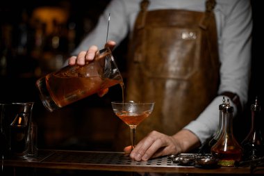 Barmen, bir alkol kokteyli ile süzer