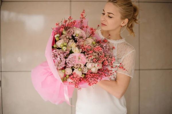 Girl holds pink bouquet of various flowers — Stock Photo, Image