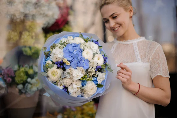 Muchacha de pie con ramo de flores blancas y azules — Foto de Stock