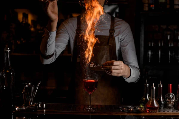 Cantinero mantiene el azúcar ardiente por encima de la bebida alcohólica — Foto de Stock