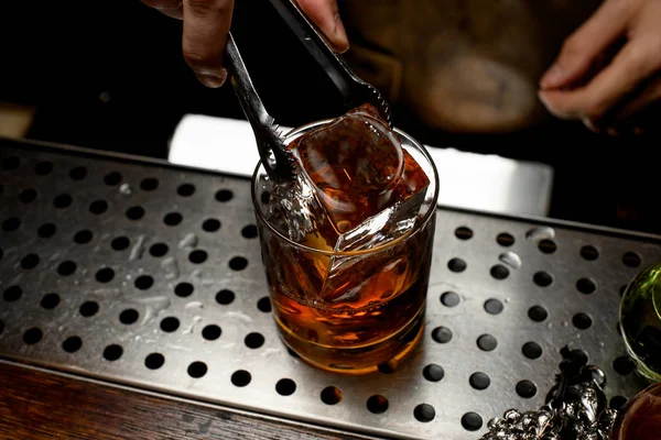 Cantinero añade un cubo de hielo en whisky —  Fotos de Stock