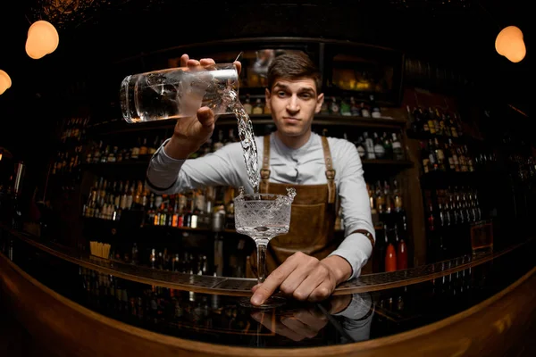 Jovem barman derramando coquetel de um frasco — Fotografia de Stock