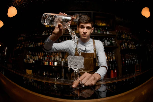 Junger Barkeeper gießt Cocktail aus dem Glas — Stockfoto