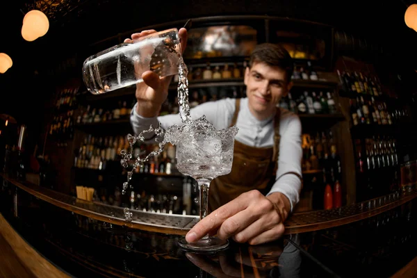 Junger Barkeeper gießt Getränk aus einem Glas — Stockfoto