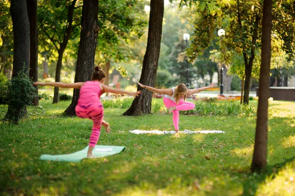 Mädchen in rosa Sportanzügen praktizieren Yoga im Park — Stockfoto