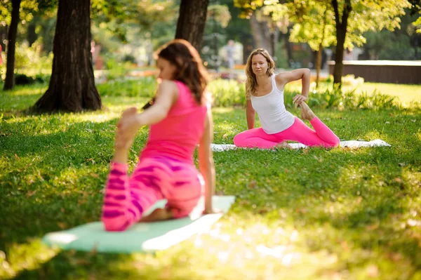 Frauen üben Yoga im Park in der krummen Affenpose — Stockfoto