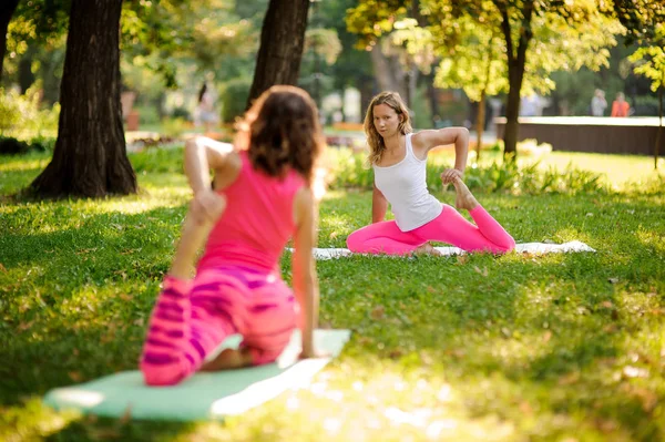 Mädchen üben Yoga im Park in der krummen Affenpose — Stockfoto