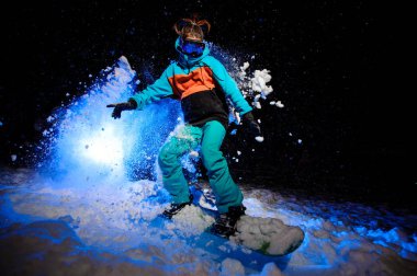 Aktif kadın snowboarder kar sürme turuncu ve mavi spor giyim giymiş
