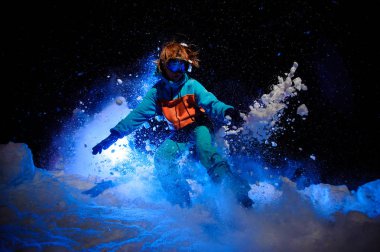 Aktif kadın snowboardcu bir turuncu ve mavi spor giyim kar üzerinde hileler yapıyor giymiş