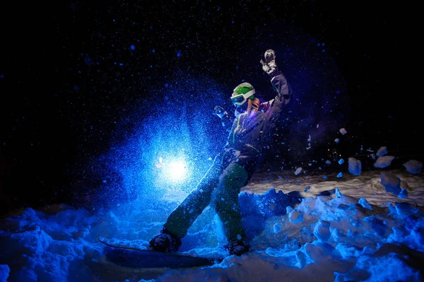 Female snowboarder dressed in a green sportswear riding on the mountain slope — Stock Photo, Image