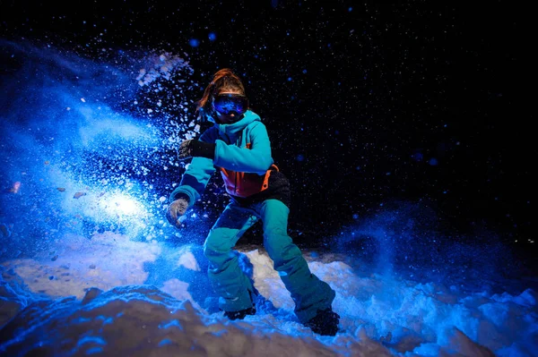 Femme active snowboarder vêtue d'un vêtement de sport orange et bleu chevauchant sur la piste de neige — Photo