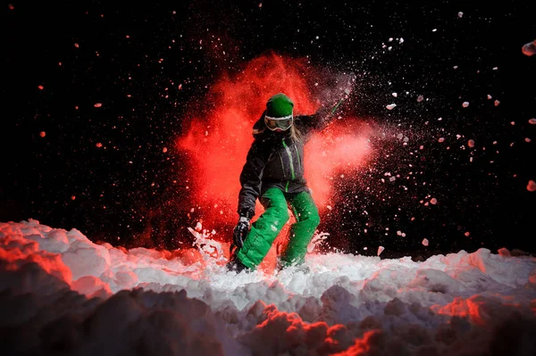 Female snowboarder dressed in a green sportswear standing on the snow slope — Stock Photo, Image