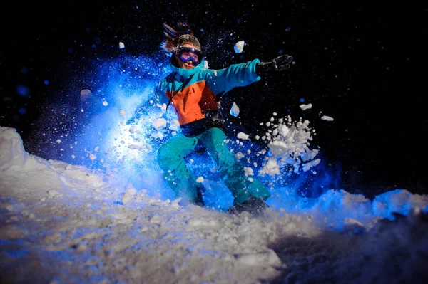 Female snowboarder dressed in a orange and blue sportswear making tricks on the snow — Stock Photo, Image