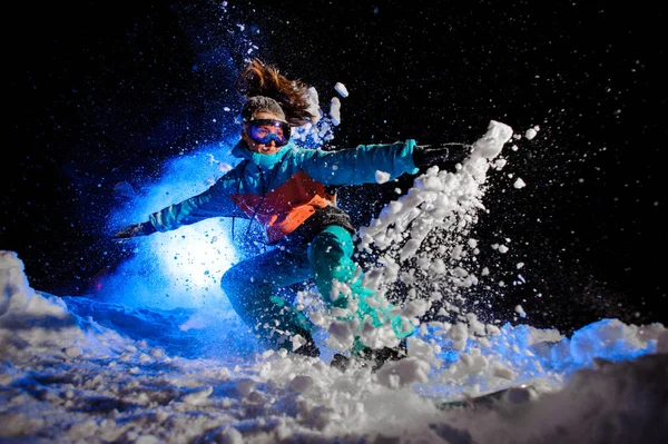 Snowboarder menina vestida com um sportswear laranja e azul fazendo truques na neve — Fotografia de Stock