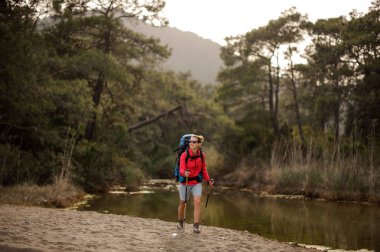 Orman Nehri kıyısından geçen kadın yolcu