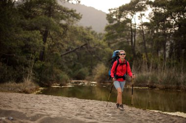 Kadın gezgin orman nehri kıyısında yürüyor
