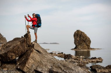 Taşlı sahilden geçen yürüyüş ekipmanları olan kadın