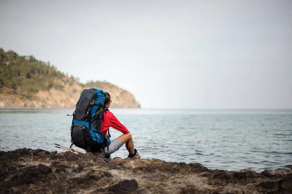 Mujer viajera en chaquetasse sienta cerca del mar —  Fotos de Stock