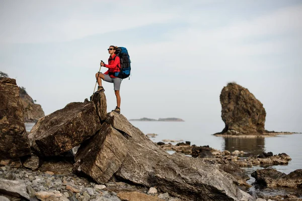 Femme avec équipement de randonnée passe par la côte de pierre — Photo