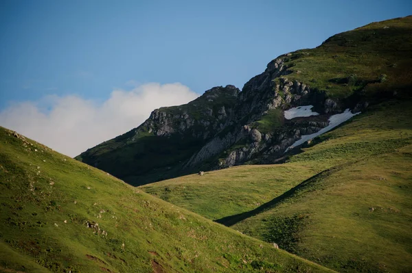 Vackert landskap av klippiga kullar täckt med gräs med snörester — Stockfoto