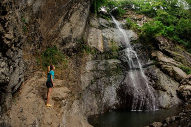 Spor giyimkadın turist şelale yakınında duruyor
