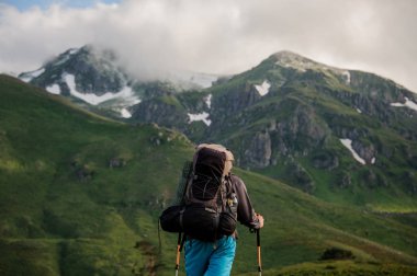 Erkek turist dağların önünde duruyor