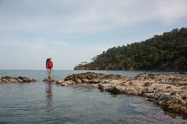 Sportig flicka som står på klippan på havet med vandring ryggsäck — Stockfoto