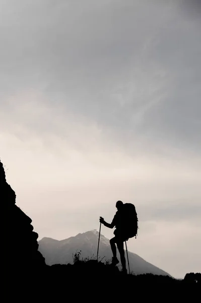 Силуэт женщина стоит на скале с рюкзаком и трости — стоковое фото