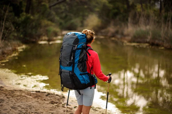 Fille vue arrière debout avec sac à dos de randonnée et regardant l'étang — Photo